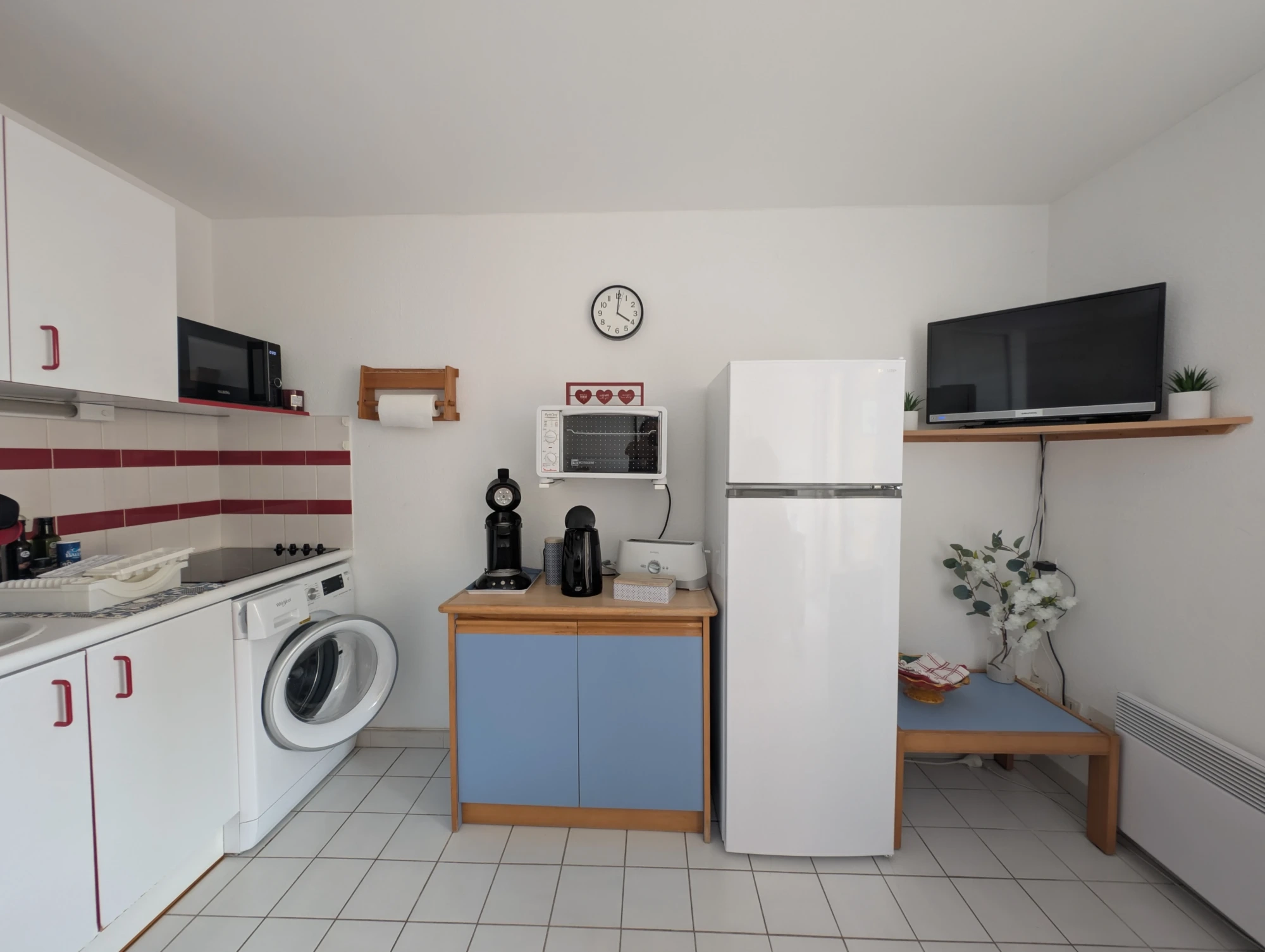 Coin cuisine équipé dans le séjour avec réfrigérateur, congélateur, lave-linge et télévision