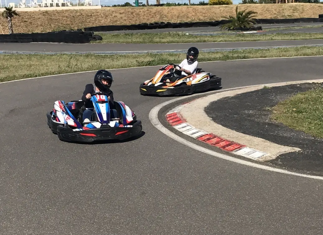 2 adolescents conduisant un kart au virage d'un circuit de karting