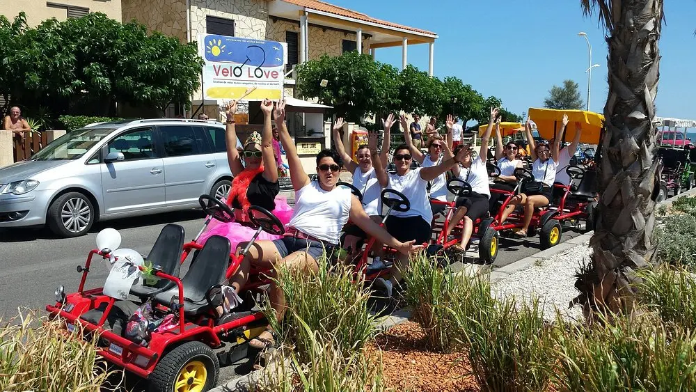 femmes portant en majorité un maillot blanc, assises sur des rosalies et levant les bras